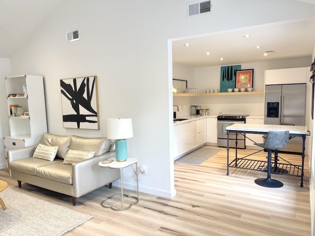 living room with high vaulted ceiling, light hardwood / wood-style floors, and sink