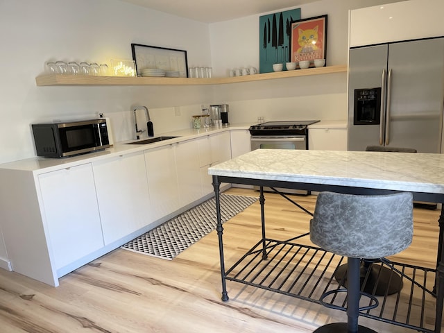 kitchen featuring light hardwood / wood-style flooring, stainless steel appliances, white cabinets, and sink