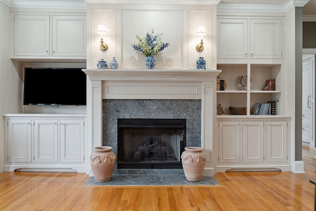 unfurnished living room featuring a high end fireplace, built in features, and light wood-type flooring