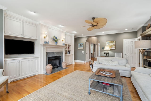 living room with crown molding, ceiling fan, a fireplace, and light hardwood / wood-style floors