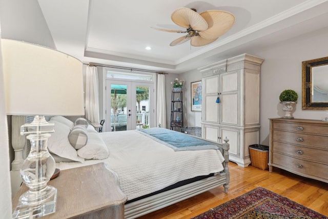 bedroom featuring crown molding, french doors, access to outside, a raised ceiling, and light wood-type flooring