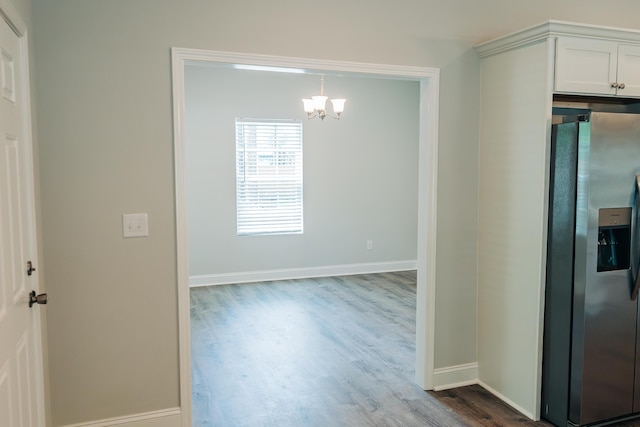 unfurnished dining area with a chandelier and hardwood / wood-style floors