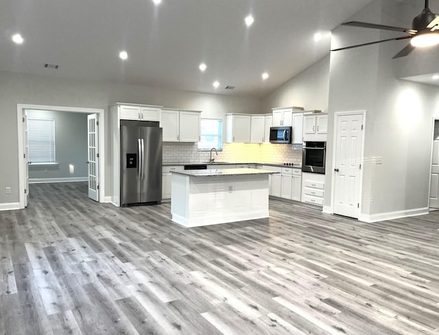 kitchen featuring sink, white cabinetry, light wood-type flooring, a kitchen island, and stainless steel appliances