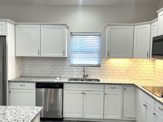 kitchen featuring tasteful backsplash, sink, white cabinets, light stone counters, and stainless steel appliances