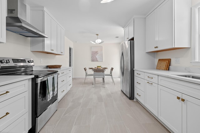 kitchen featuring light countertops, wall chimney exhaust hood, white cabinetry, and stainless steel appliances
