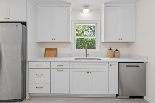 kitchen featuring white cabinets, light stone countertops, appliances with stainless steel finishes, and a sink