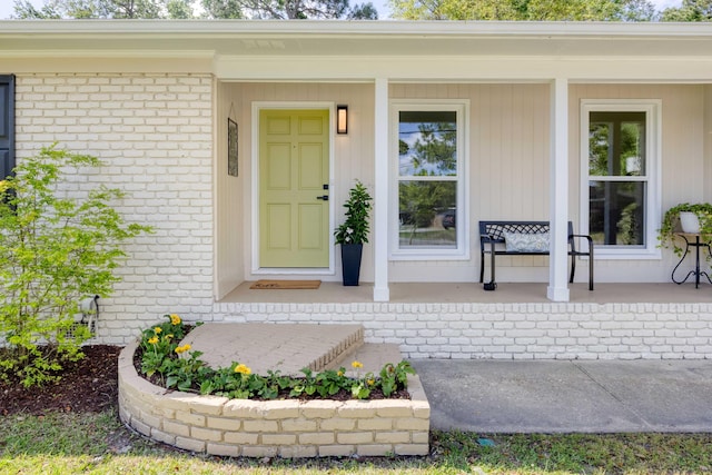 property entrance with a porch and brick siding