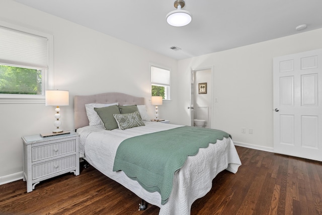 bedroom with baseboards, connected bathroom, wood finished floors, and visible vents