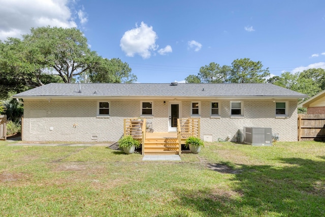 rear view of house featuring fence, central AC unit, a yard, and brick siding