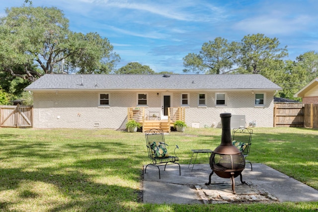 back of property with an outdoor fire pit, brick siding, a lawn, a patio, and fence private yard