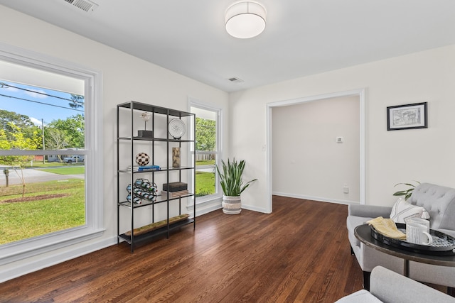 living area with baseboards, visible vents, and wood finished floors
