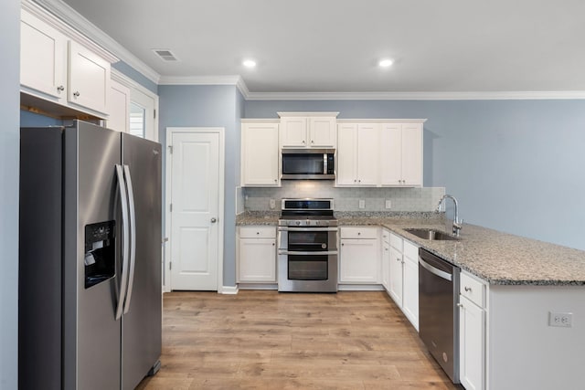 kitchen with sink, white cabinets, ornamental molding, and appliances with stainless steel finishes