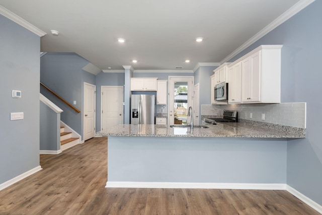 kitchen featuring kitchen peninsula, appliances with stainless steel finishes, white cabinetry, and sink