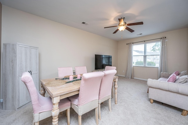 dining room with a ceiling fan, light colored carpet, visible vents, and baseboards