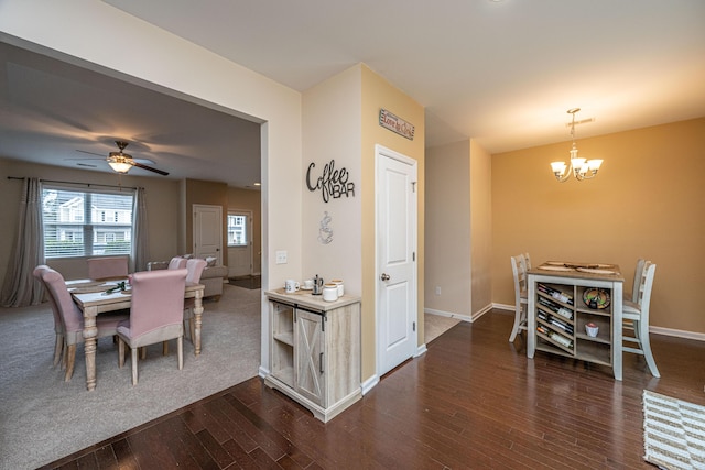 dining room featuring dark wood finished floors, ceiling fan with notable chandelier, and baseboards