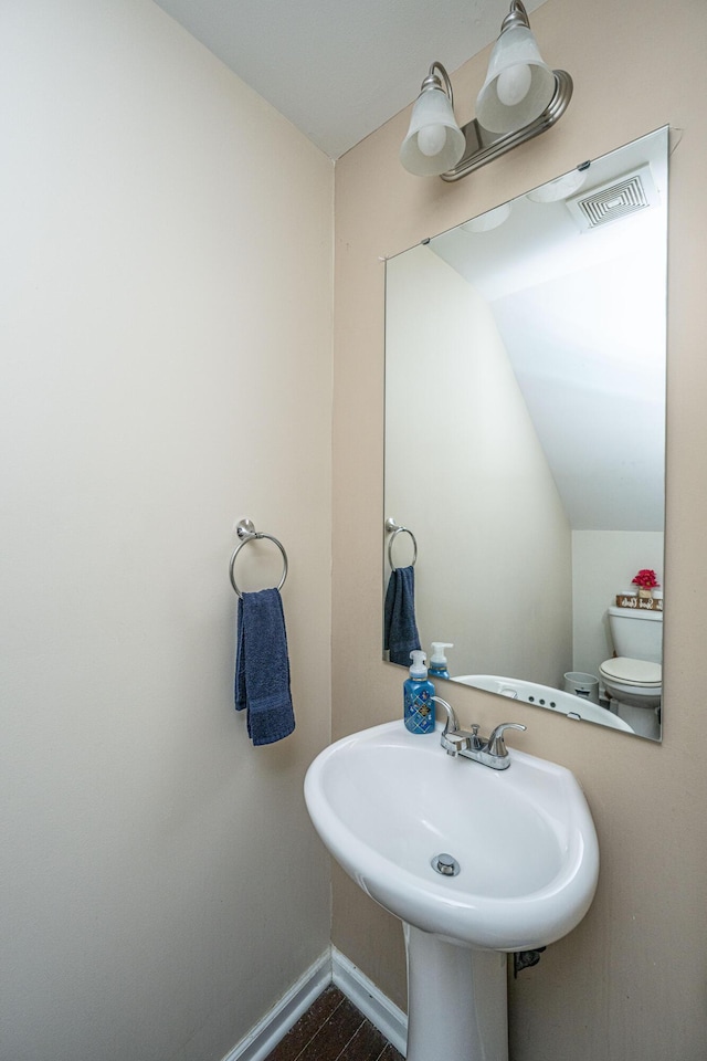 bathroom featuring wood finished floors, baseboards, visible vents, a sink, and toilet