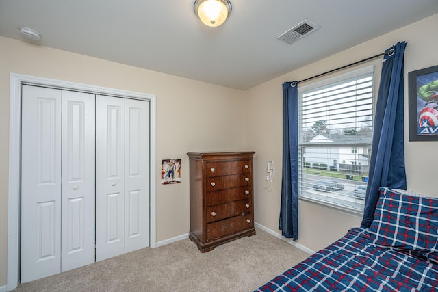 carpeted bedroom with visible vents, baseboards, and a closet