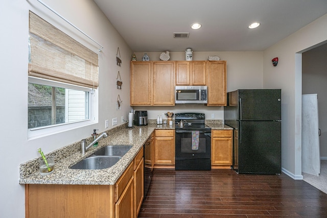 kitchen featuring light stone counters, visible vents, dark wood finished floors, a sink, and black appliances