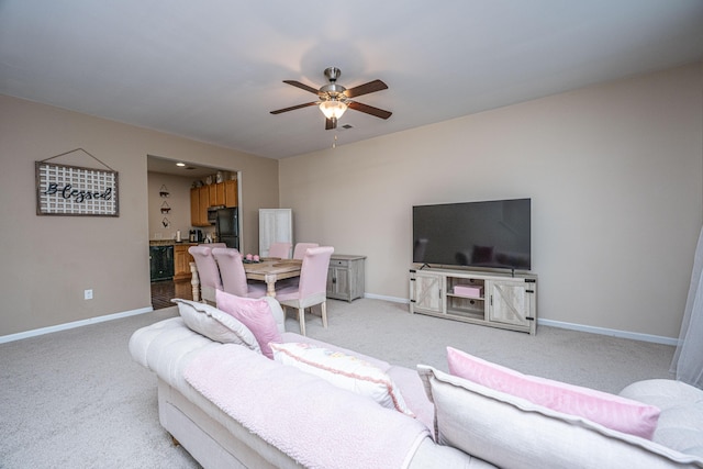 living area featuring a ceiling fan, baseboards, and light carpet