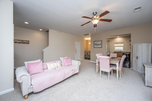 living area with visible vents, light colored carpet, baseboards, and a ceiling fan