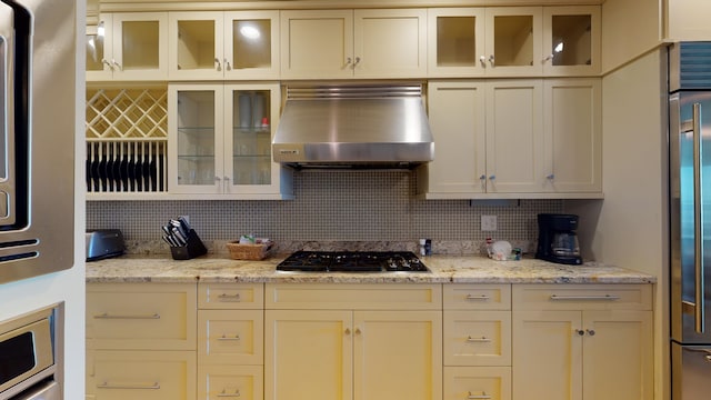 kitchen with extractor fan, tasteful backsplash, black gas stovetop, and light stone counters