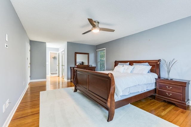 bedroom with light hardwood / wood-style floors, ceiling fan, and a textured ceiling