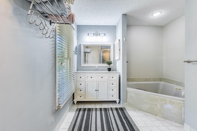 bathroom with vanity, tile patterned floors, a relaxing tiled tub, and a textured ceiling