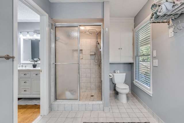 bathroom featuring a shower with shower door, vanity, toilet, and tile patterned flooring