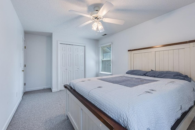 bedroom featuring ceiling fan, light carpet, a closet, and a textured ceiling