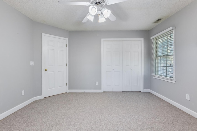 unfurnished bedroom featuring a closet, a textured ceiling, carpet flooring, and ceiling fan