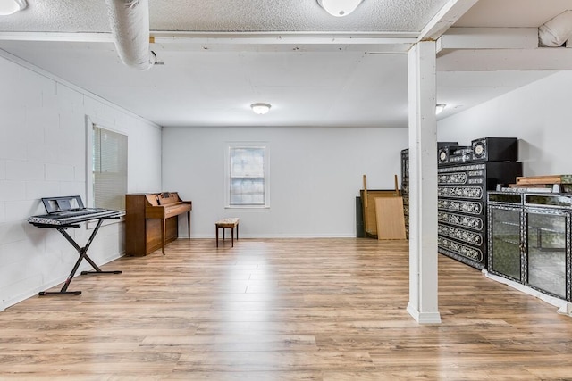 basement featuring light hardwood / wood-style floors and a textured ceiling