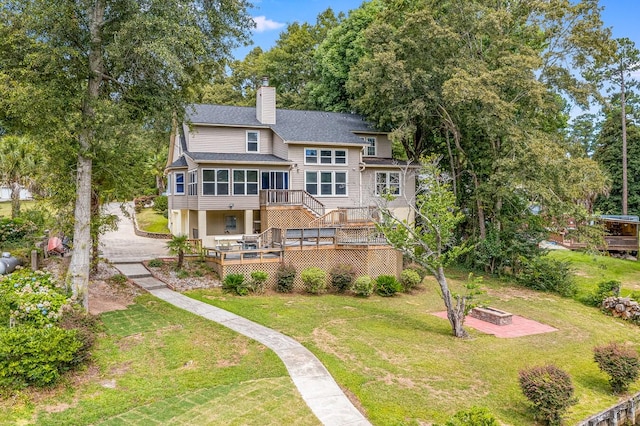 rear view of property featuring a deck, a sunroom, and a yard