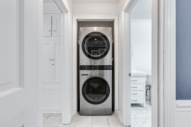 washroom with a textured ceiling and stacked washer / drying machine