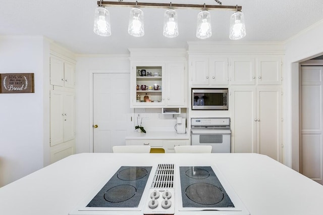 kitchen featuring a textured ceiling, decorative light fixtures, white oven, stainless steel microwave, and white cabinets