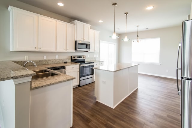 kitchen featuring appliances with stainless steel finishes, a sink, dark wood-style floors, a kitchen island, and white cabinetry