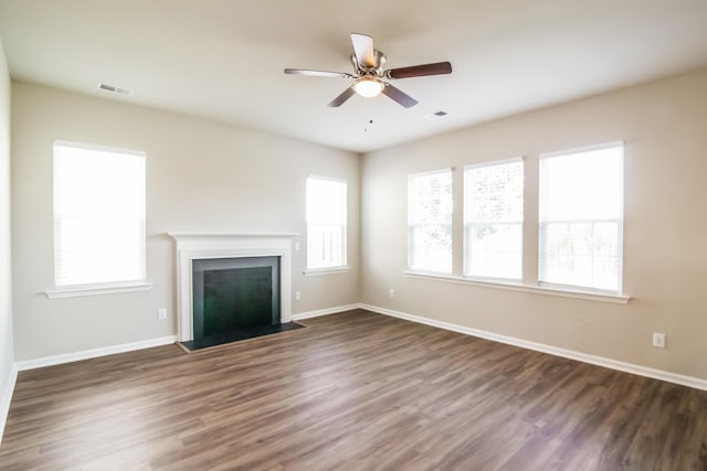 unfurnished living room with plenty of natural light, dark wood finished floors, and baseboards