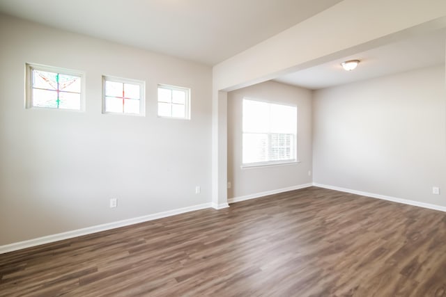 empty room with dark wood-style flooring and baseboards
