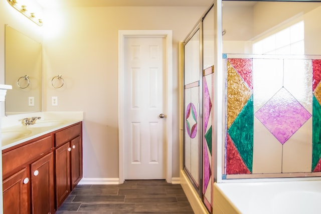 bathroom featuring wood finished floors, a shower stall, double vanity, baseboards, and a bath