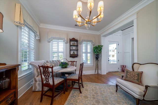 dining area with wood finished floors, visible vents, crown molding, and a notable chandelier