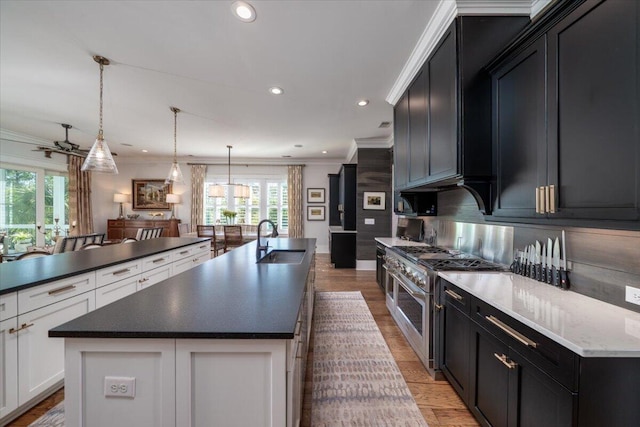 kitchen with an island with sink, a healthy amount of sunlight, a sink, crown molding, and double oven range