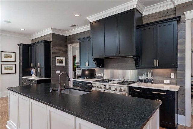 kitchen with high end stainless steel range, visible vents, a sink, and crown molding