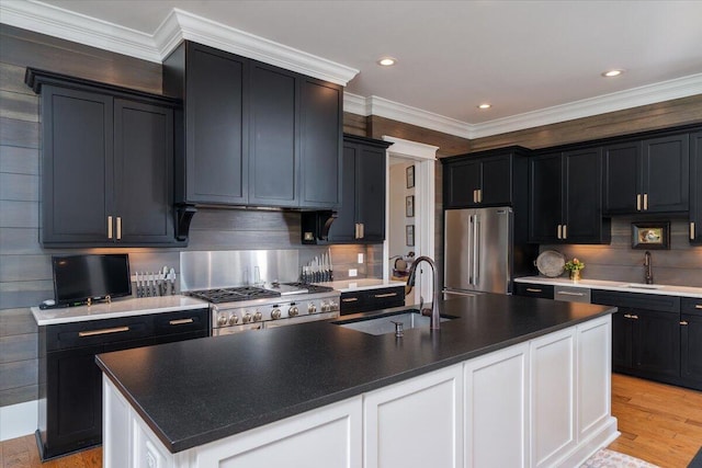 kitchen featuring a sink, high end refrigerator, backsplash, dark cabinetry, and range