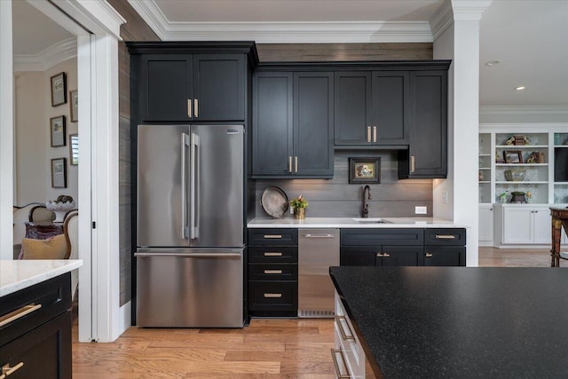 kitchen with light wood-style flooring, a sink, decorative backsplash, high end fridge, and ornamental molding
