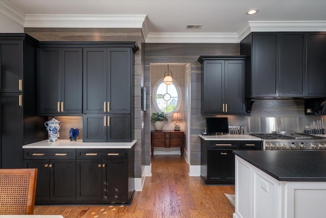 kitchen with stove, backsplash, visible vents, light wood-style floors, and crown molding