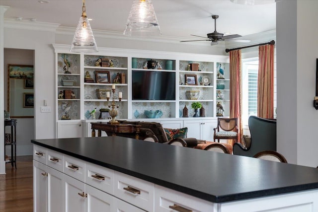 kitchen with dark wood finished floors, dark countertops, ornamental molding, and ceiling fan
