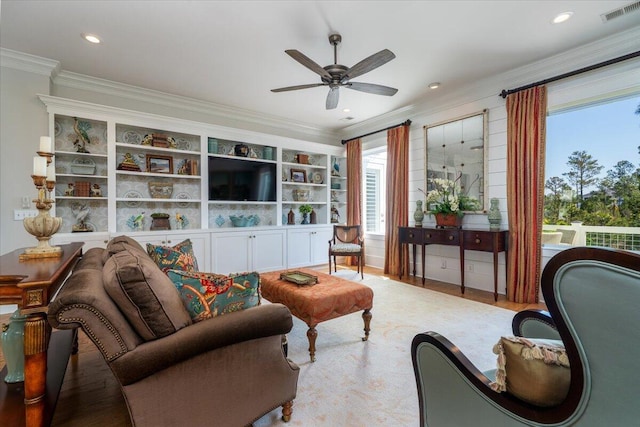 living area featuring wood finished floors, a ceiling fan, visible vents, and ornamental molding