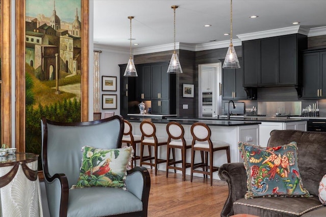 kitchen featuring backsplash, dark countertops, crown molding, and a sink