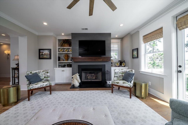 living room with visible vents, baseboards, ceiling fan, a fireplace, and ornamental molding