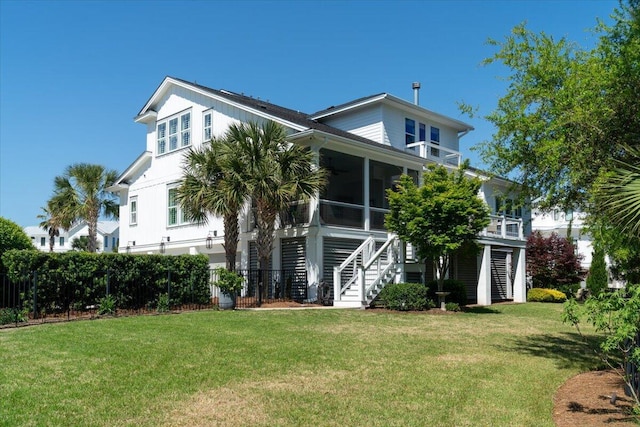 view of front of home with a front lawn, stairway, fence, and a sunroom