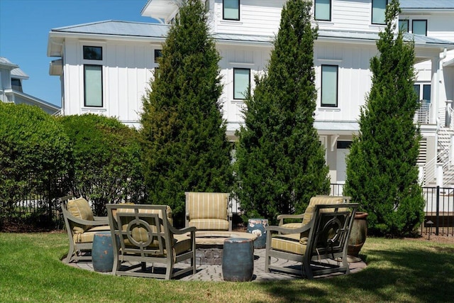 back of property featuring board and batten siding, a lawn, a patio, and a fire pit